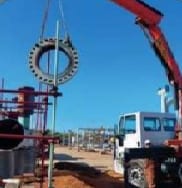 Camión con brazo hidráulico manipulando una brida en obra