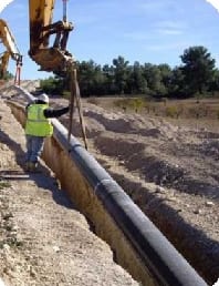 Cuadrilla bajando tubería a una zanja durante el tendido de una línea de flujo